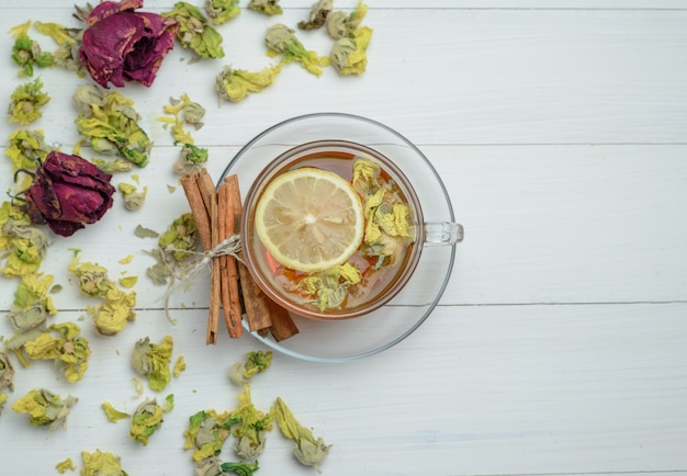 Lemony thee in een kopje met gedroogde kruiden, kaneelstokjes plat lag op een houten oppervlak