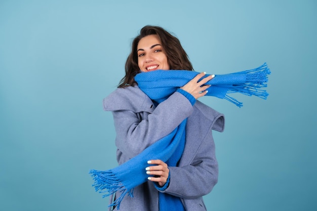Lente herfst portret van een vrouw in een blauwe gebreide trui, sjaal en grijze jas, vrolijk poseren, glimlachend, in afwachting van de lente