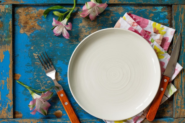 Lente of moederdag tafel instelling bord bestek en servet op blauwe houten tafel