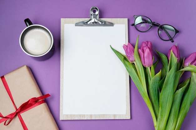 Lentetijd achtergrond met witte lege lege paarse tulpen en een kopje koffie op een violette achtergrond Bovenaanzicht plat lag