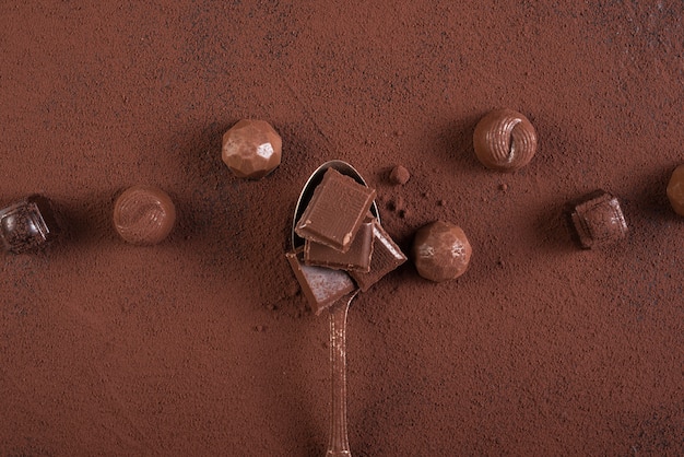 Lepel met chocoladereep vierkanten snoepjes en cacaopoeder