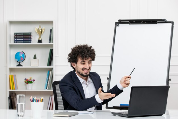 Leraar brunette instructeur met computer in pak en whiteboard in klas lachend