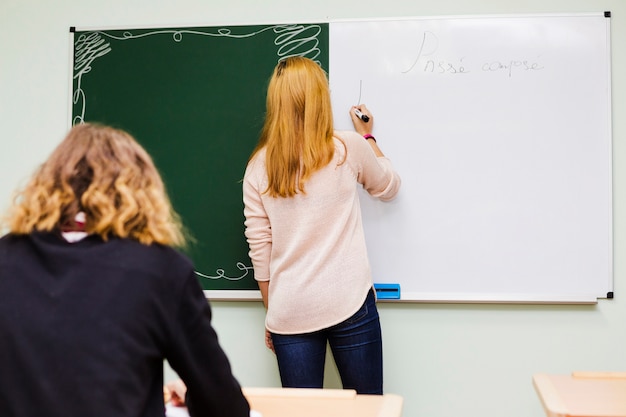 Gratis foto leraar die op whiteboard voor leerling schrijft