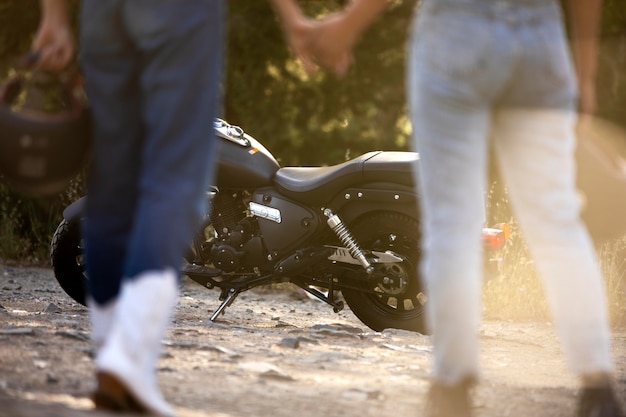 Lesbisch koppel hand in hand in de buurt van motorfiets tijdens een roadtrip Gratis Foto