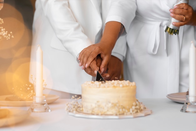 Gratis foto lesbisch koppel snijdt de taart aan op hun bruiloft