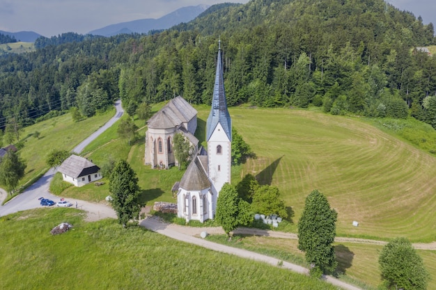 Gratis foto lese kerk op een heuvel bedekt met groen onder het zonlicht in slovenië