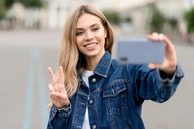 Leuk blond meisje dat een selfie vredesteken neemt