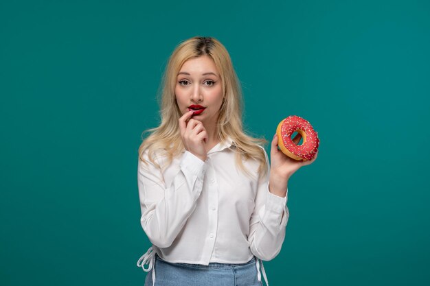 Leuk meisje blond mooi jong meisje in een wit netjes shirt denken aan het eten van een donut
