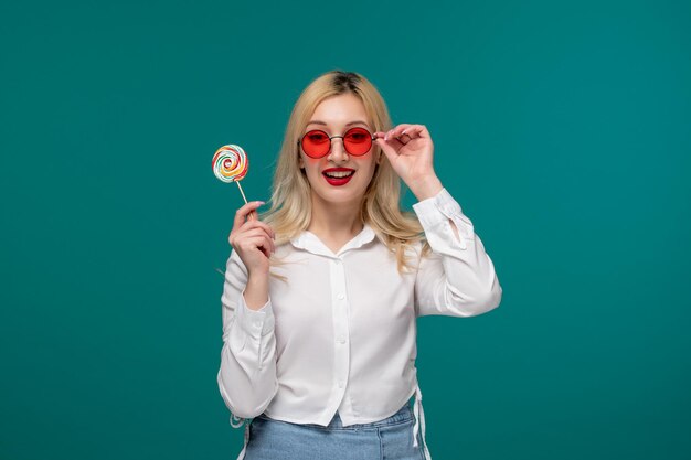 Leuk meisje blond mooi jong meisje in een wit netjes shirt met lolly in rode zonnebril