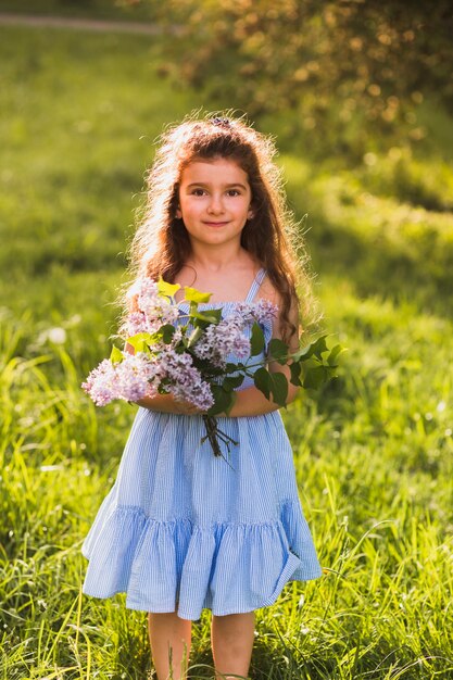 Leuk meisje dat zich op gras met de bos van de holdingsbloem bevindt