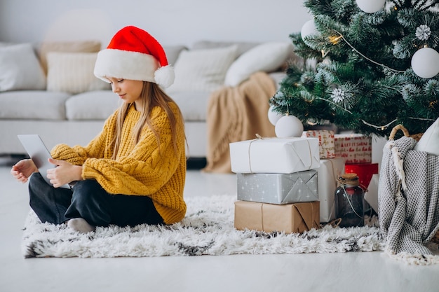 Leuk meisje met behulp van computer door kerstboom