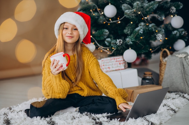 Leuk meisje met behulp van computer door kerstboom