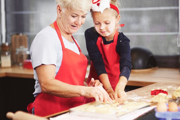 Leuk meisje met haar oma die deeg maakt