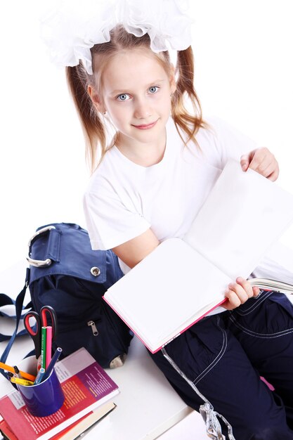 Leuk meisje met schooltas zittend op het bureau