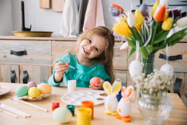 Leuk meisje schilderij eieren voor Pasen aan tafel