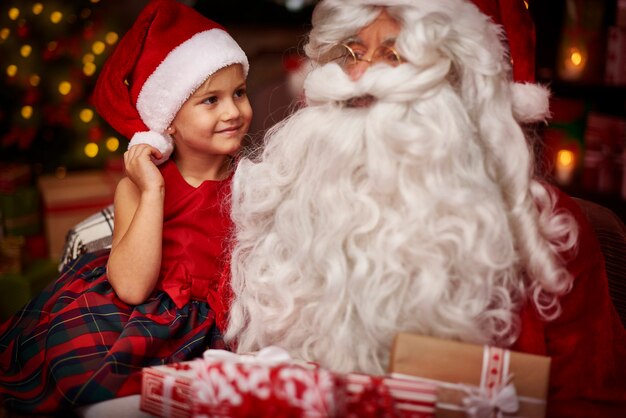 Leuk meisje, zittend op de knieën van de kerstman