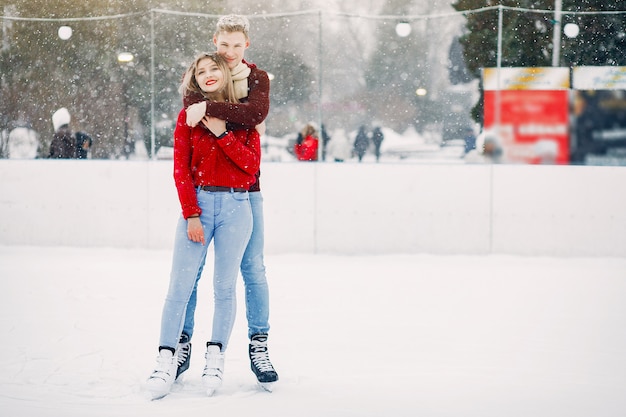 Leuk paar in rode sweaters die pret in een ijsarena hebben