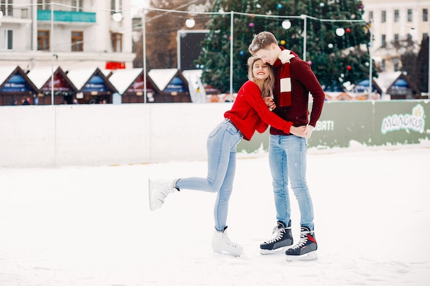 Leuk paar in rode sweaters die pret in een ijsarena hebben