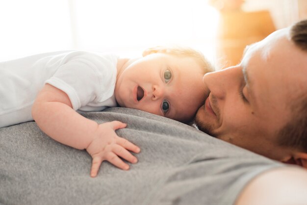 Leuke baby die op vader ligt