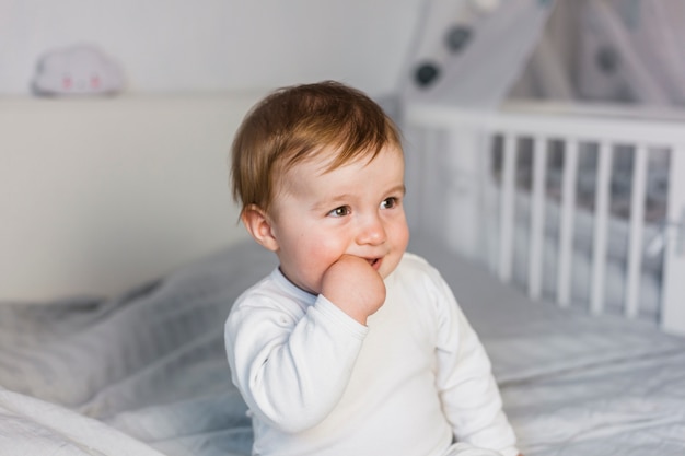 Leuke blonde baby in wit bed