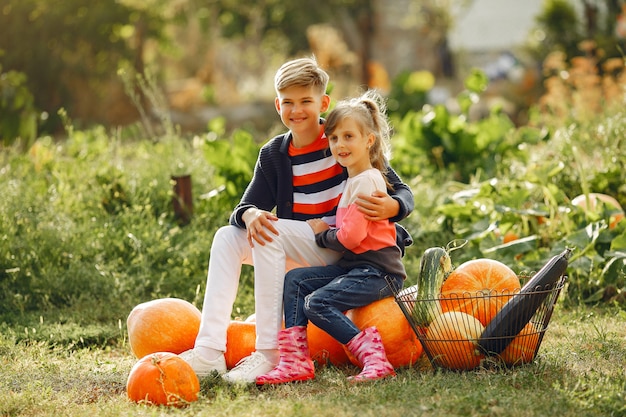 Leuke childresnzitting op een tuin dichtbij vele pompoenen