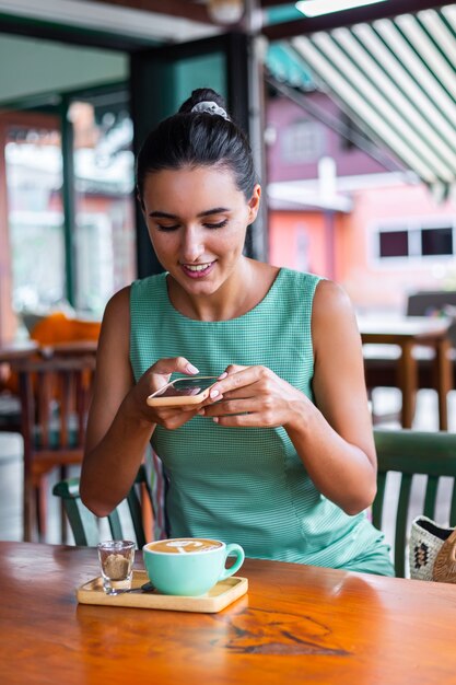 Leuke elegante rustige gelukkige vrouw in groene zomerjurk zit met koffie in café genieten van ochtend