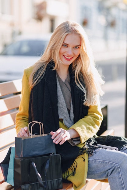 Leuke gelukkig aantrekkelijke blonde vrouw met pakketten op straat bij zonnig warm weer