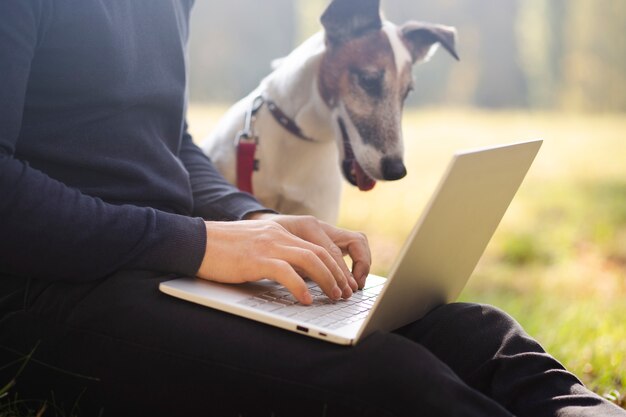 Leuke hond met eigenaar en laptop in park