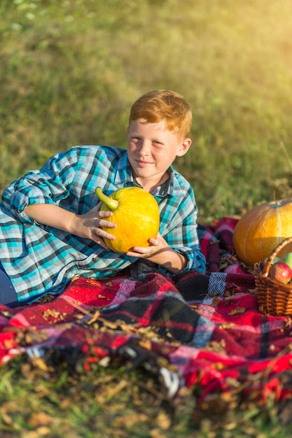 Gratis foto leuke jonge jongen die een gele pompoen houdt