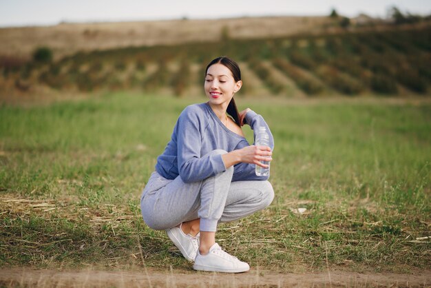 Leuke jonge vrouw in sportkleren met fles water