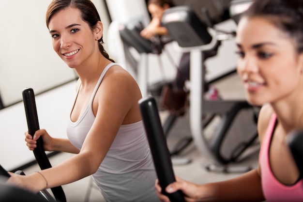 Gratis foto leuke jonge vrouwen die gymles volgen op elliptische trainers