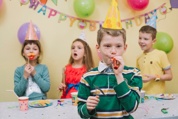 Leuke jongen die noisemaker op verjaardagspartij blaast