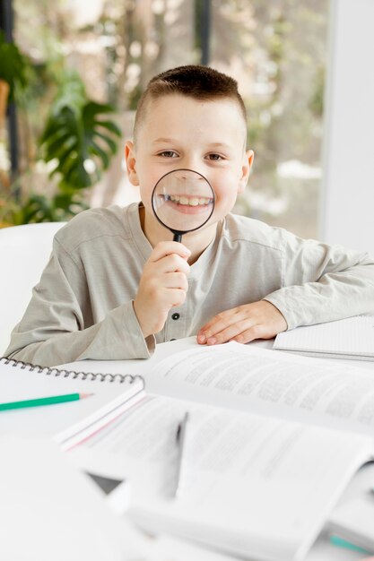 Leuke jongen die rond met een vergrootglas voor de gek houdt