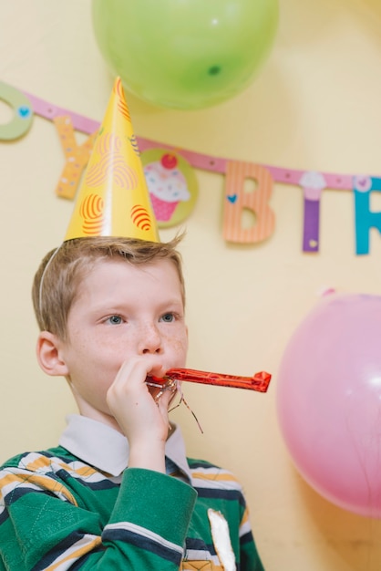 Leuke jongen met noisemaker op feestje