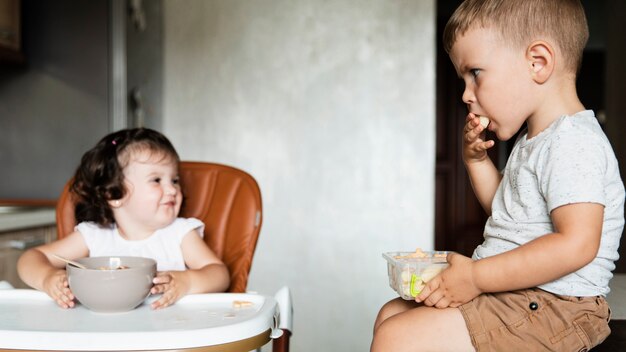Leuke kinderen eten en kijken naar elkaar