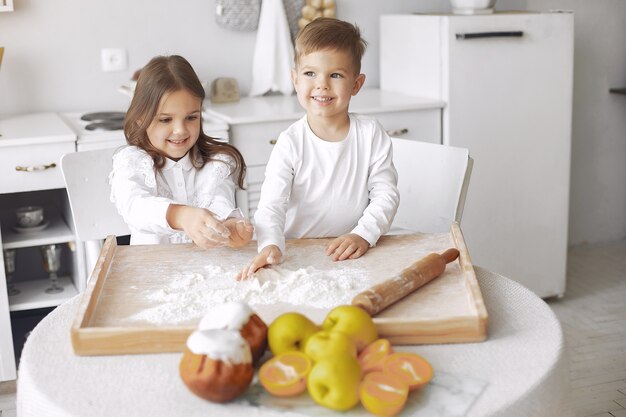 Leuke kleine kinderen die in een keuken met deeg zitten