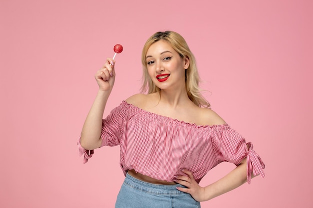 Gratis foto leuke meisjes mooie jonge dame met rode lippenstift in roze blouse zwaaiend in de lucht met de lolly