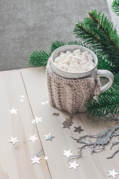 Leuke mok vol marshmallows omringd door kerstversieringen op tafel