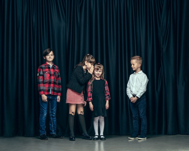 Leuke stijlvolle kinderen op donkere ruimte. De mooie tienermeisjes en de jongen die zich verenigen