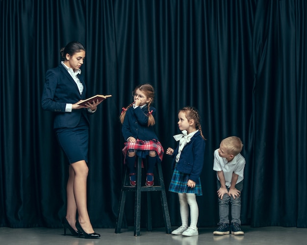 Leuke stijlvolle kinderen op donkere studio. de mooie tiener meisjes en jongen staan samen