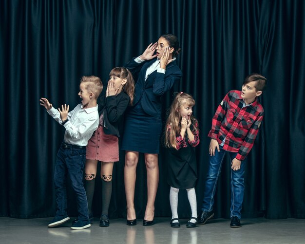 Leuke stijlvolle kinderen op donkere studio. mooie tienermeisjes en jongen die zich verenigen