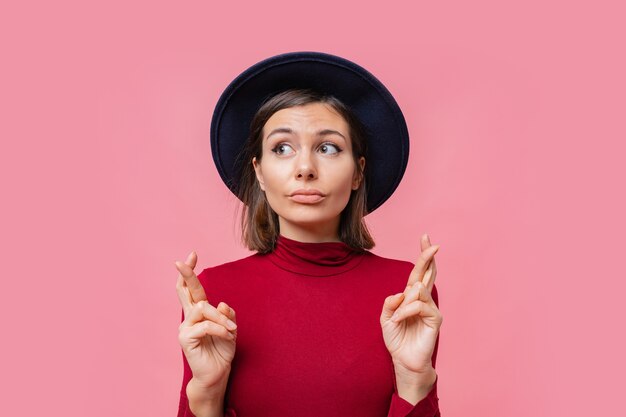 Leuke vrolijke vrouw wil haar best doen om haar vingers gekruist te houden, heeft het beste, gekleed in rode jamper geïsoleerd