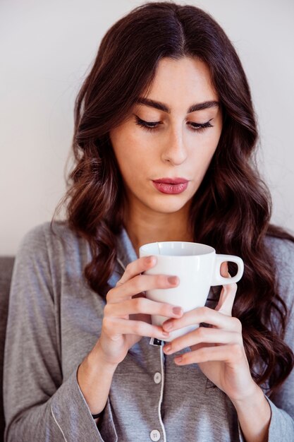 Leuke vrouw die bij thee blaast