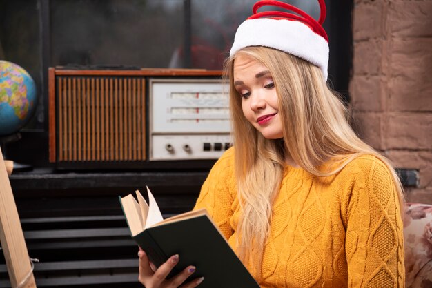 Leuke vrouw in kerstmuts zit en leest een boek