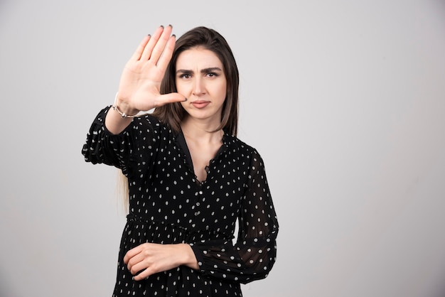 Leuke vrouw in zwarte jurk die haar hand toont.