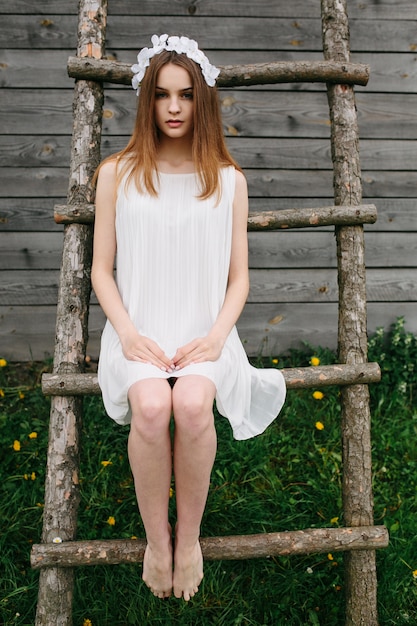 Gratis foto leuke vrouw, zittend op een houten ladder