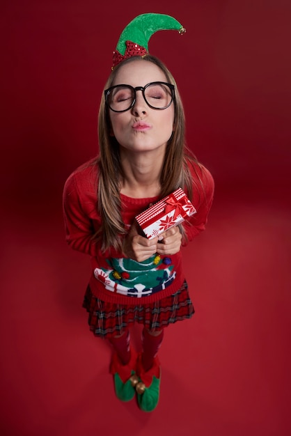 Gratis foto leuke vrouwelijke nerd met klein cadeautje gekleed in kerstkleren