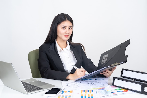 levensstijl mooie Aziatische zakelijke jonge vrouw met behulp van laptopcomputer en slimme telefoon op een bureau