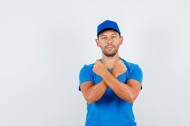 Levering man houden gebalde vuisten gekruist in blauw t-shirt