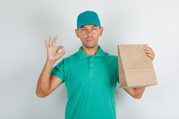 Levering man in groen t-shirt en pet doet ok teken met papieren zak